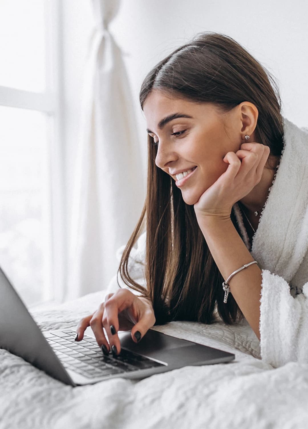 Relaxed woman in a bed looking at her laptop